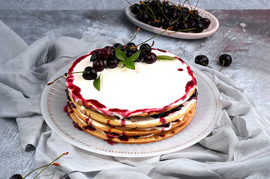 Cherry Shortbread Dessert: Layers of buttery shortbread biscuit, lathered with fresh cream and juicy cherries, topped with a beautifully arranged cherry layer and a delicate caramel web. Served with a box of homemade custard for an extra touch of indulgence.